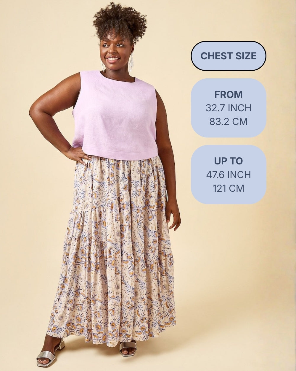 A woman modeling a sleeveless light pink top and a long beige floral maxi skirt against a warm beige studio background. Three blue informational callouts on the right read chest size, from 32.