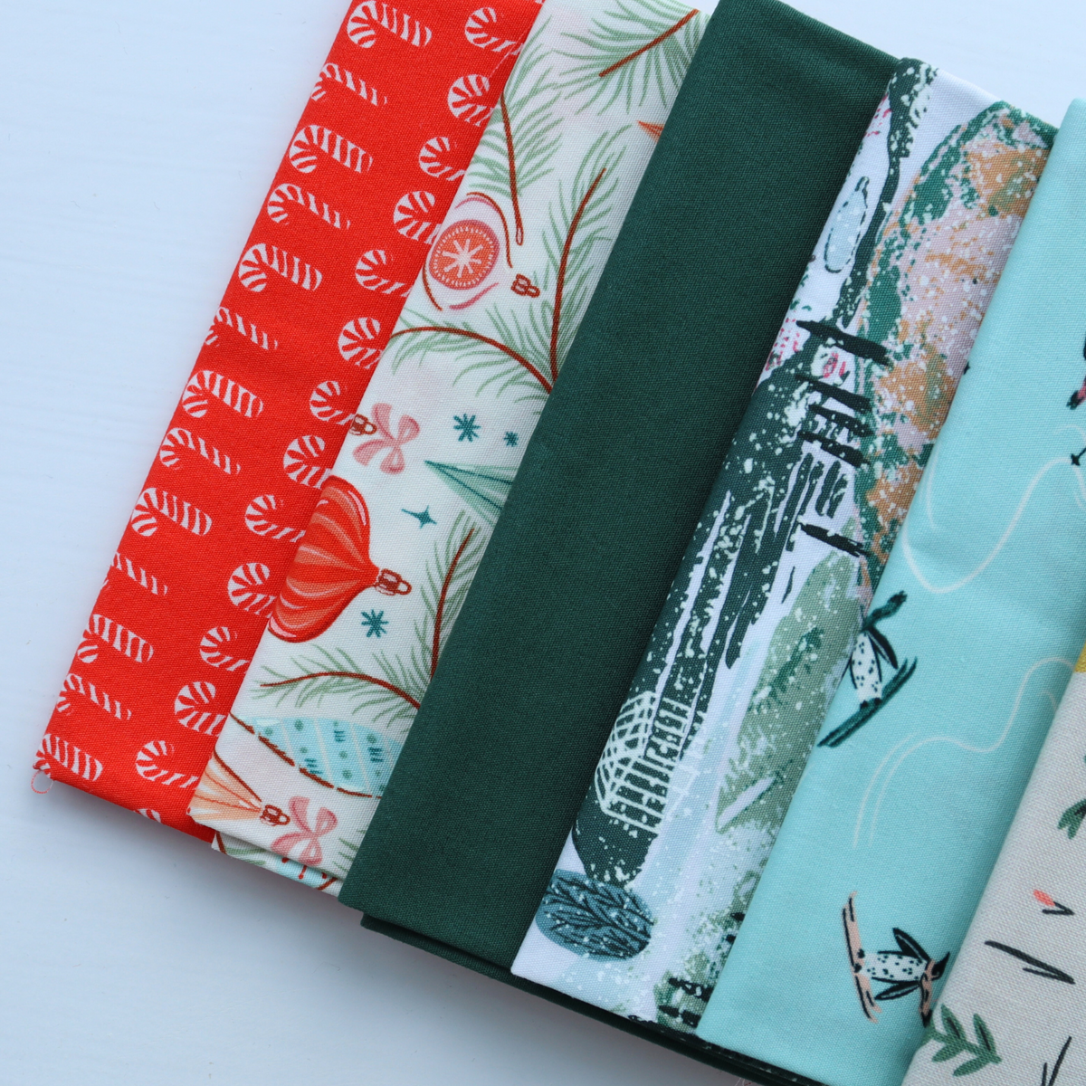 Collection of fabric rolls with festive patterns on a light blue background
