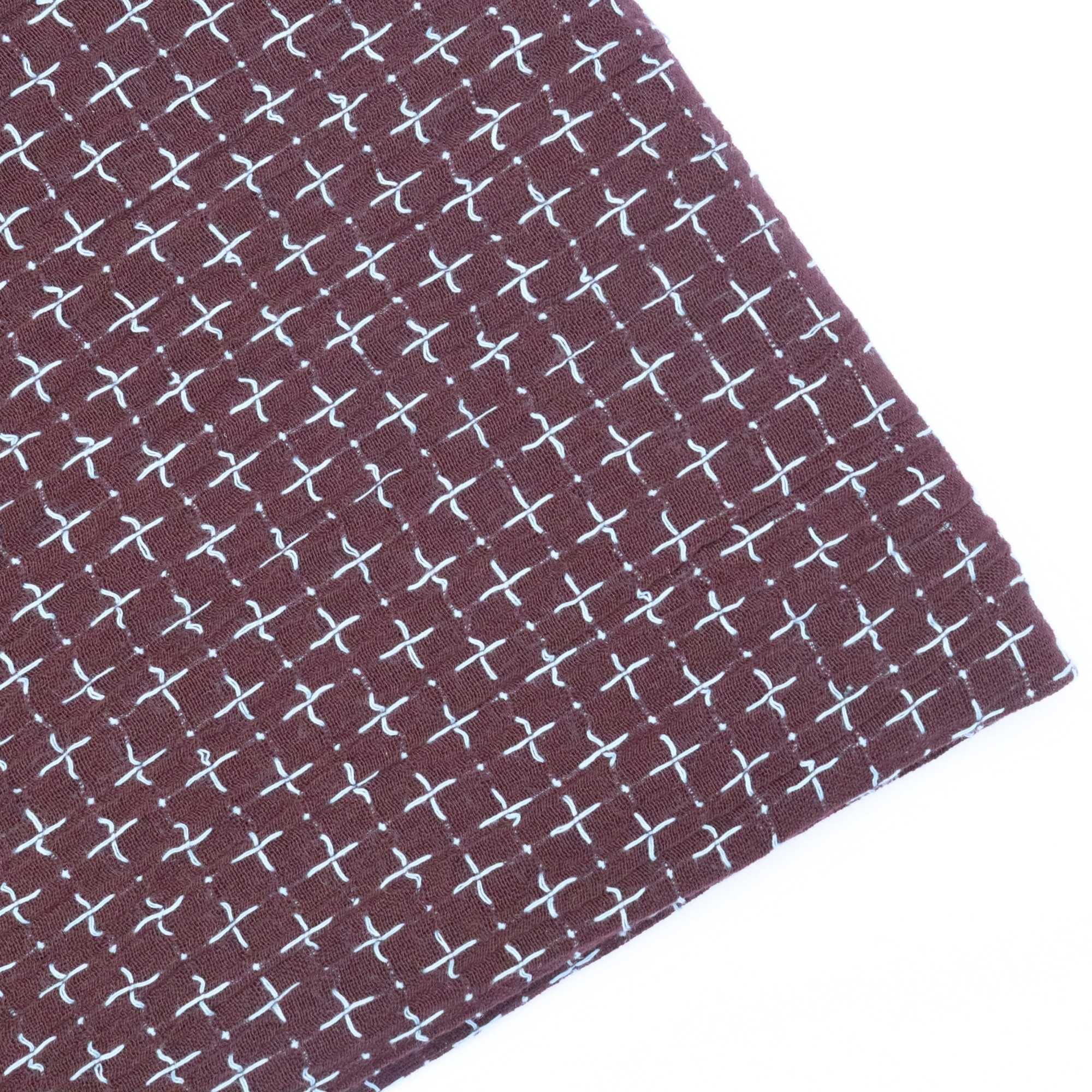 Close-up of fabric with white cross pattern on a brown background