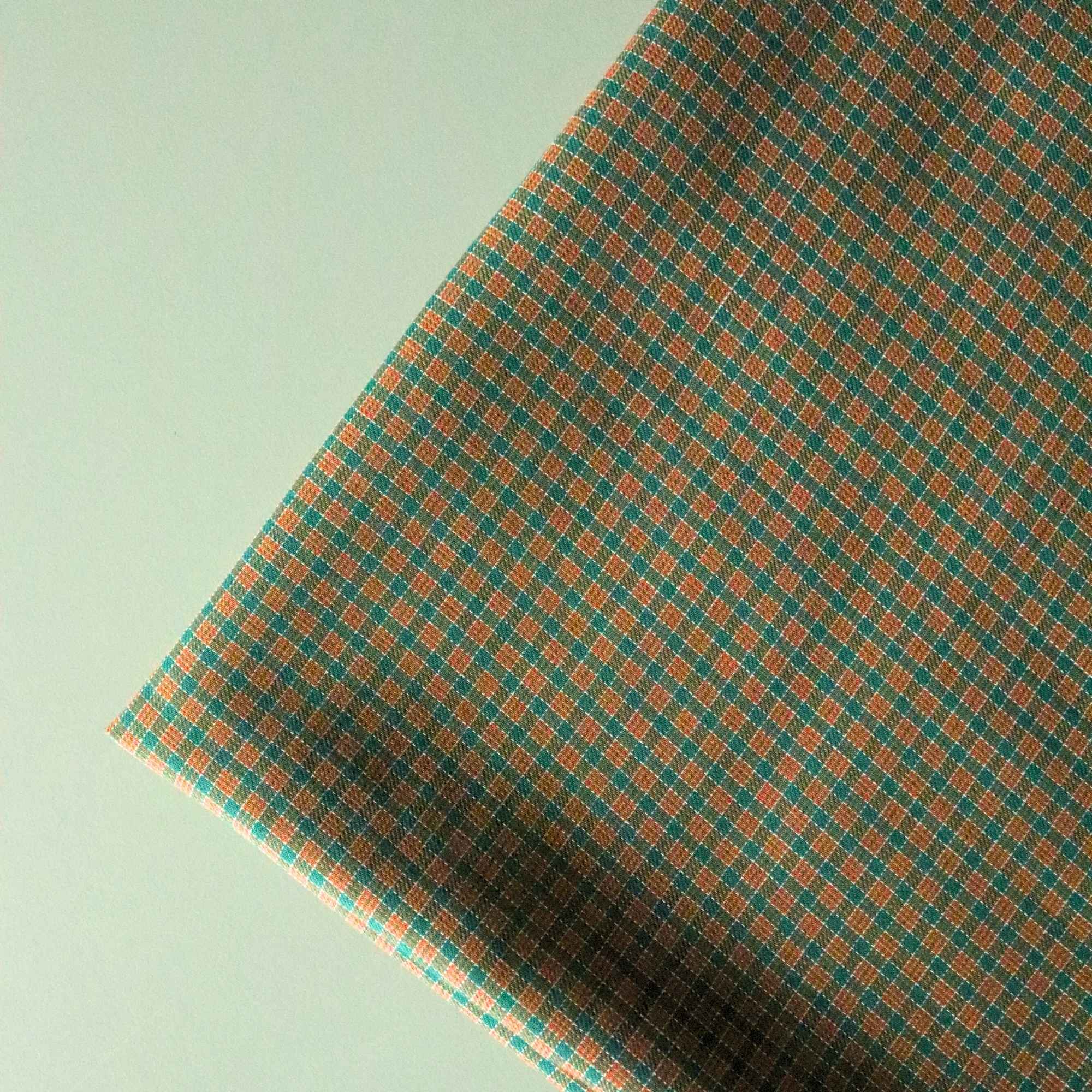Toffee Cotton fabric with green checkered patterns lying folded on the table