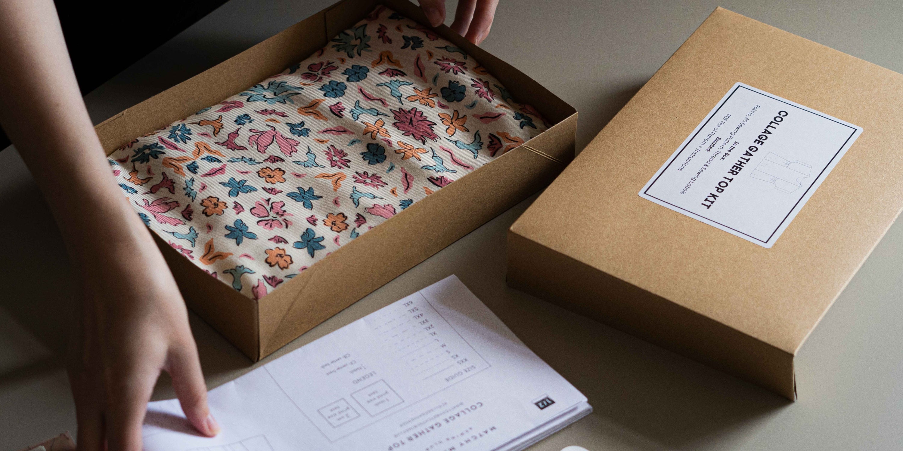 Unboxing of a floral-patterned viscose fabric in from a sewing project box, adding the pattern copy into the box.
