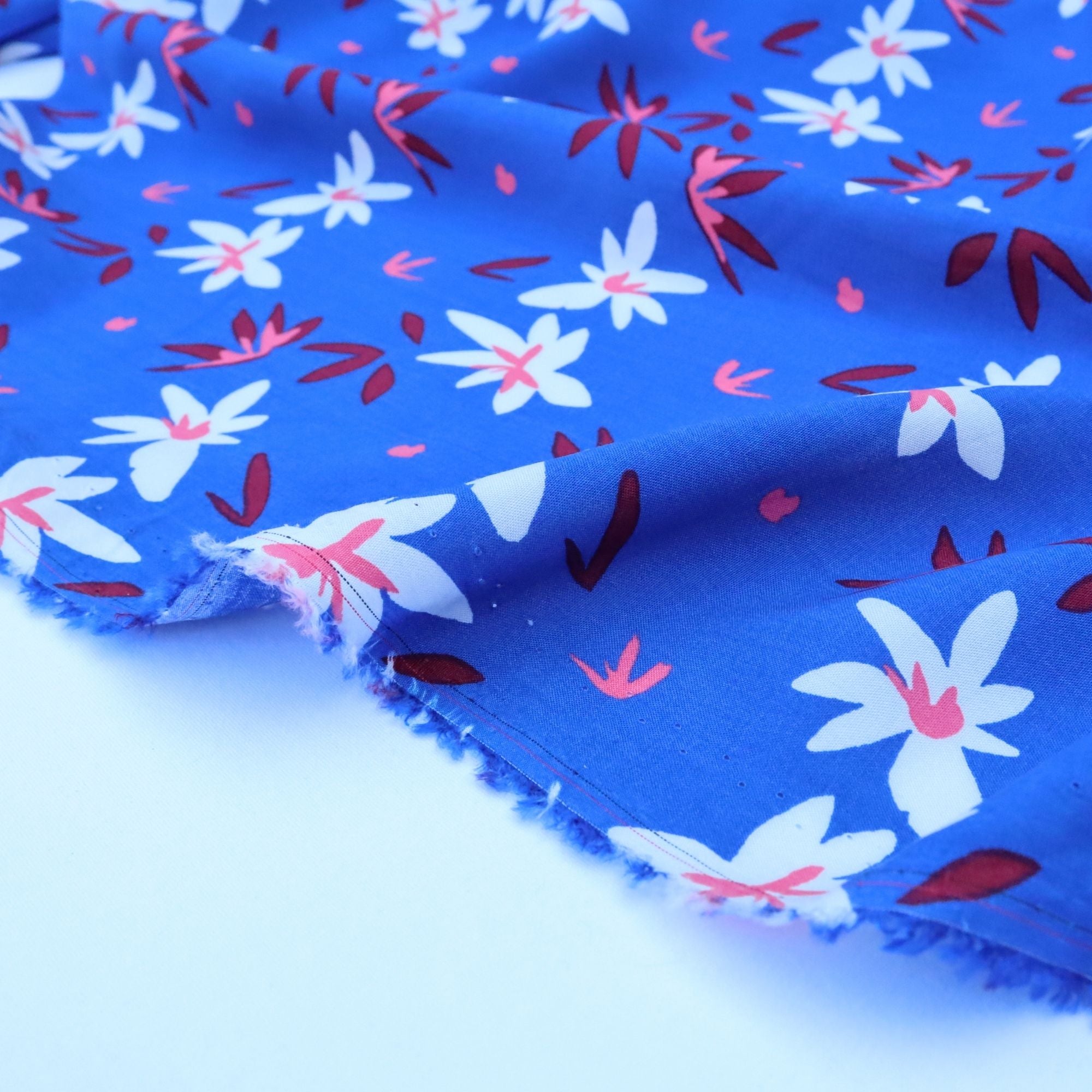 Floral fabric with white flowers and red leaves on a blue background