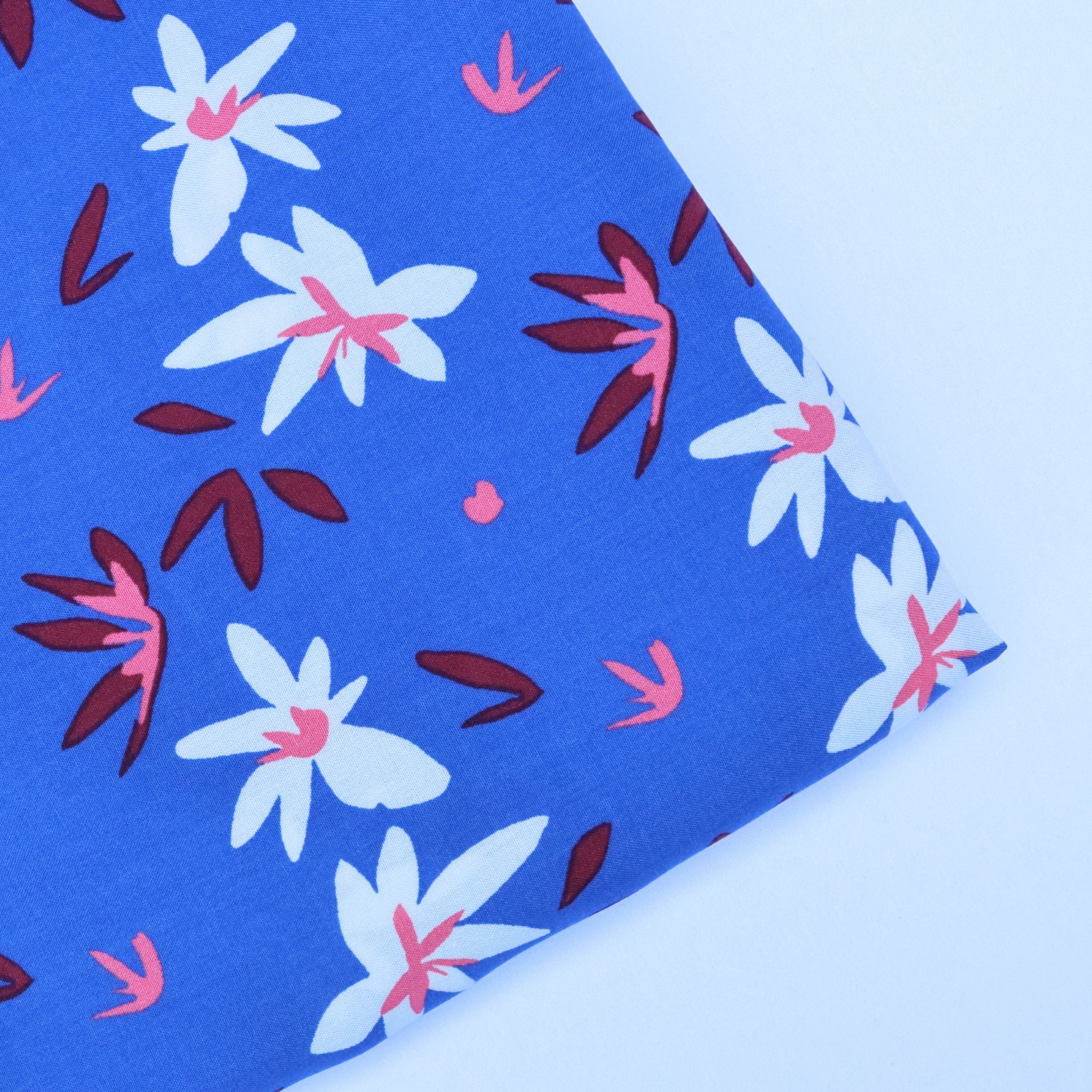 Floral patterned fabric with white, pink, and red flowers on a blue background