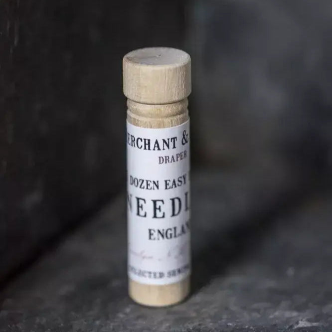 Small wooden tube with a label saying "dozen easy sewing needles&