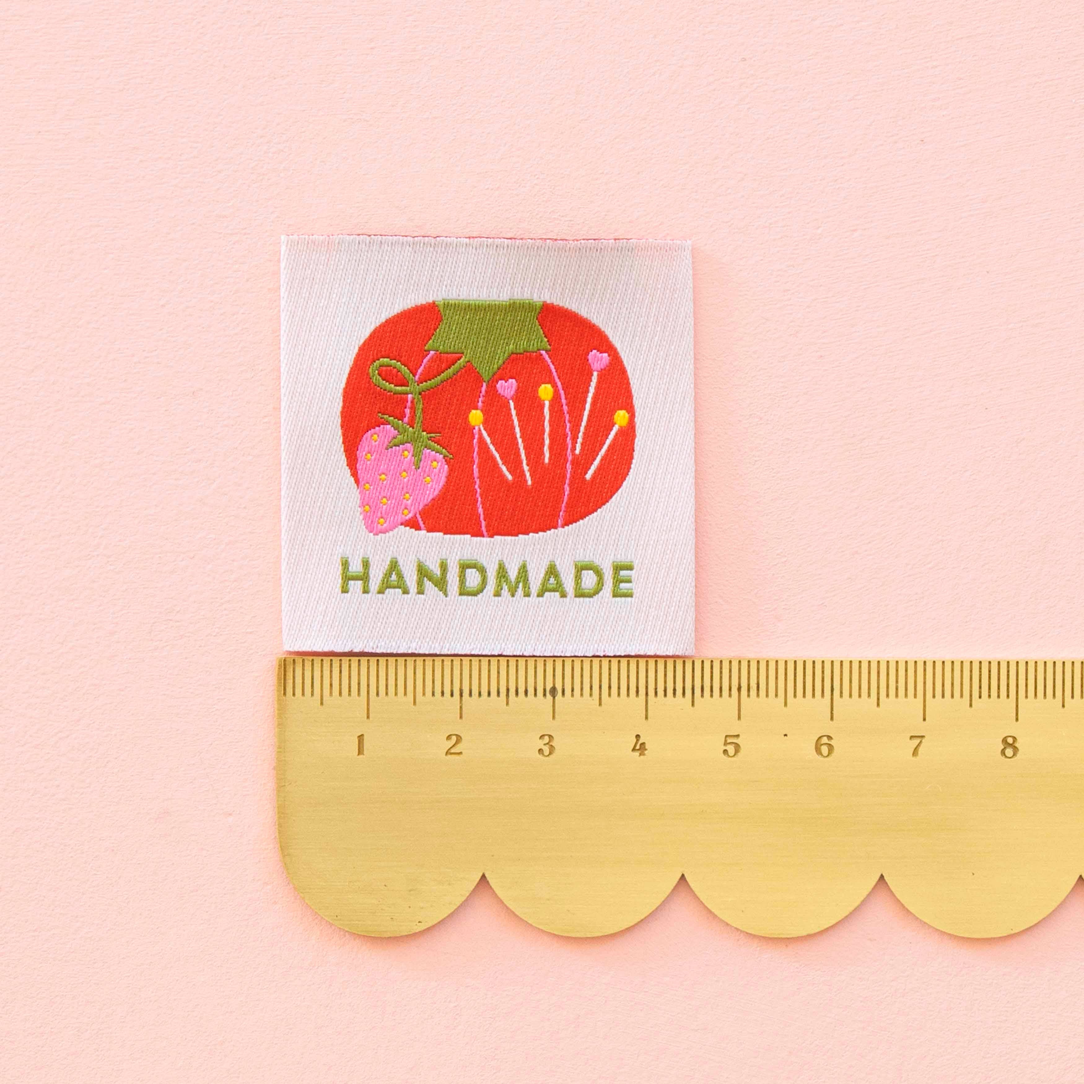 Sewing Label saying "Handmade" with a tomato pin cushion design on white background. Measured with a ruler 4.5cm.