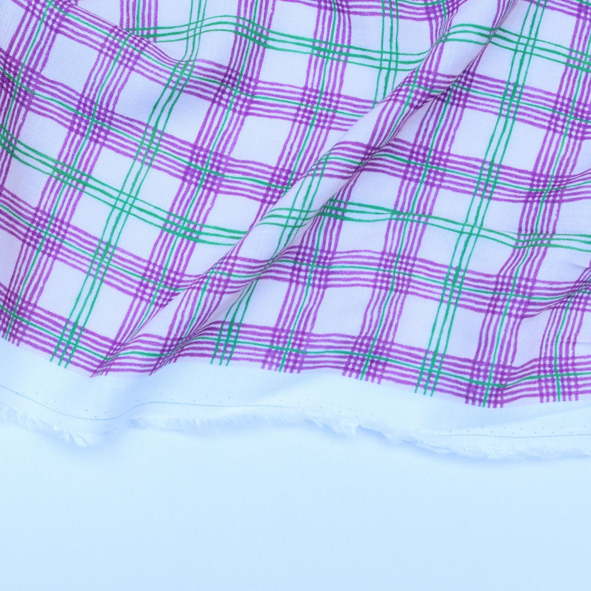 Close-up of fabric with purple and green plaid pattern on a white background
