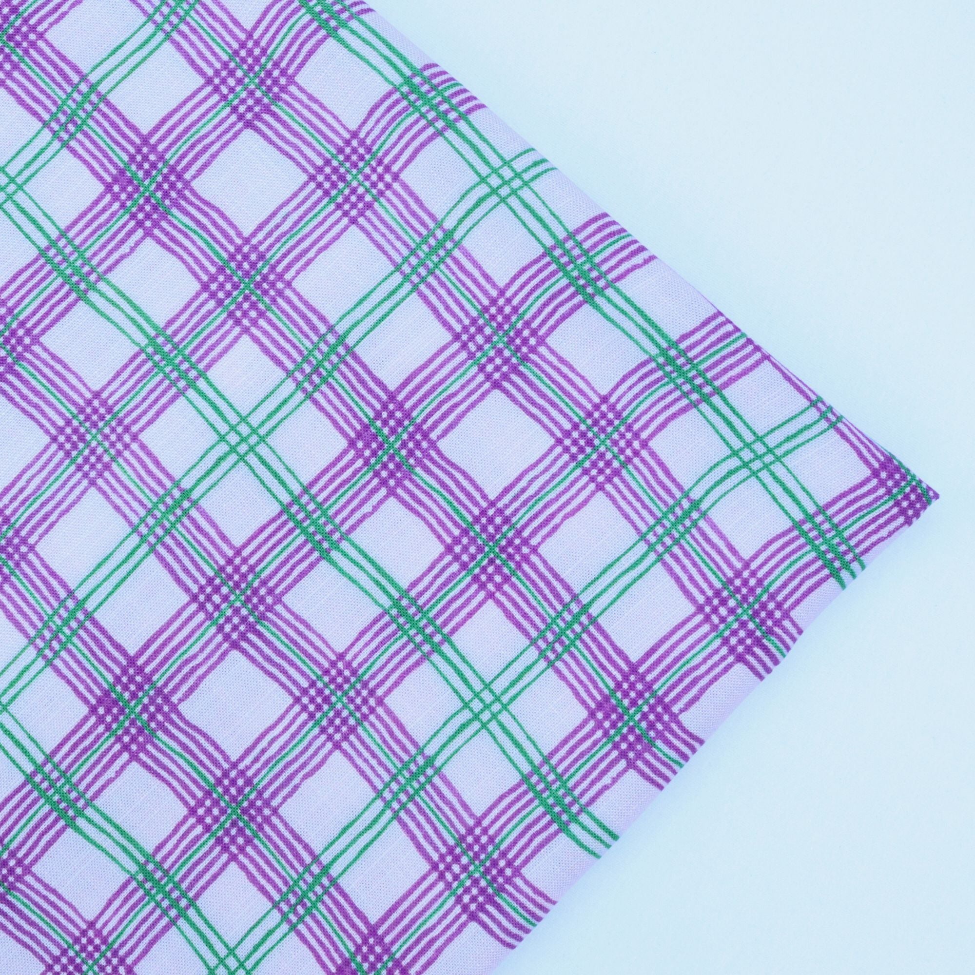 Plaid fabric with purple and green lines on a light blue background