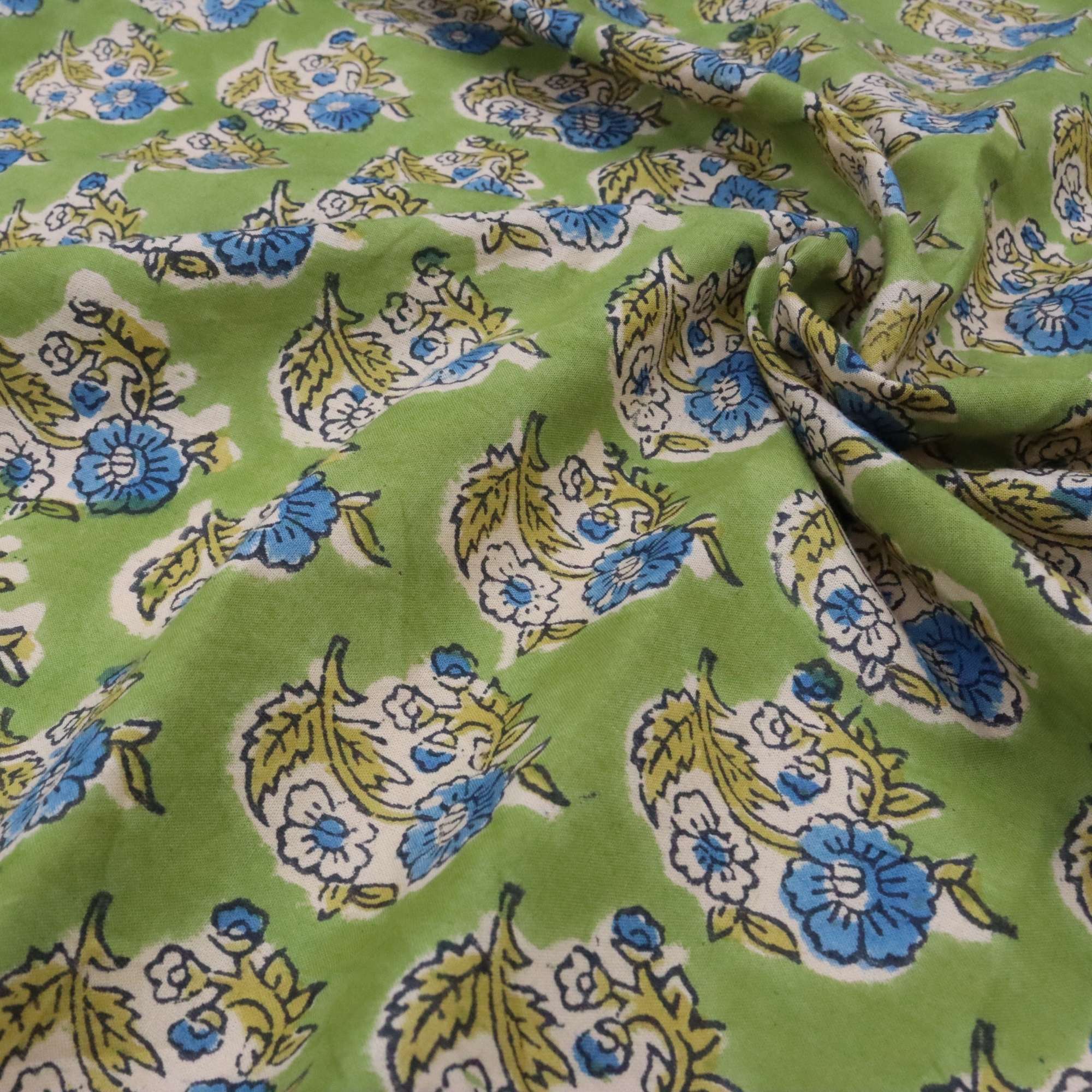 Floral patterned fabric with blue, yellow, and white flowers on a green background