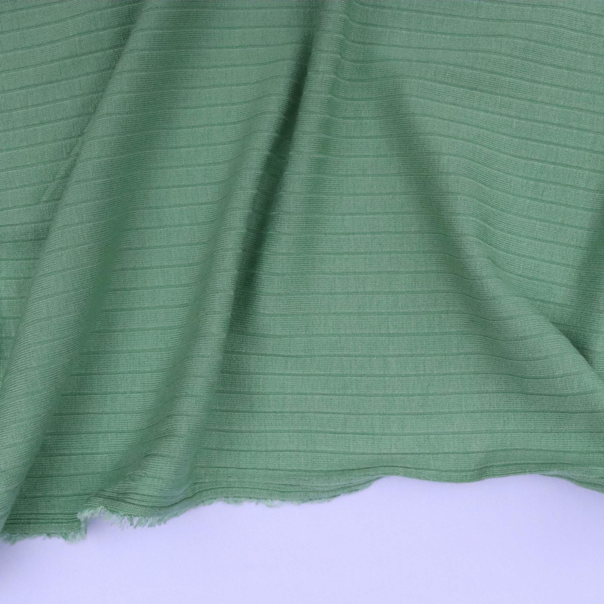 Green fabric with a ribbed texture on a white background