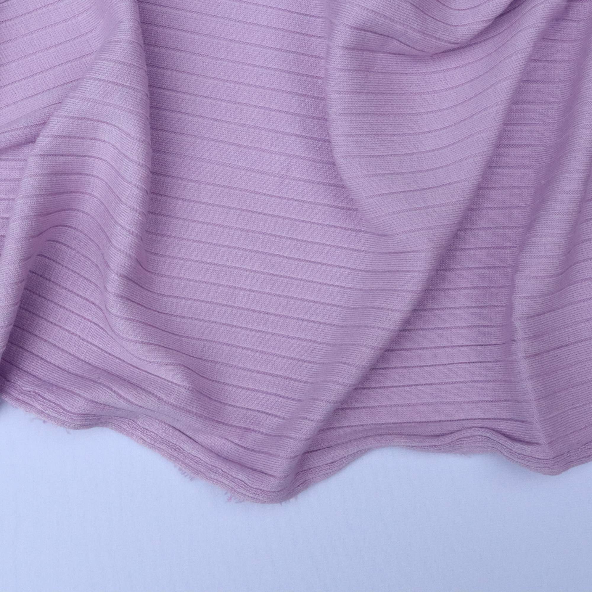 Close-up of purple ribbed fabric on a light gray background