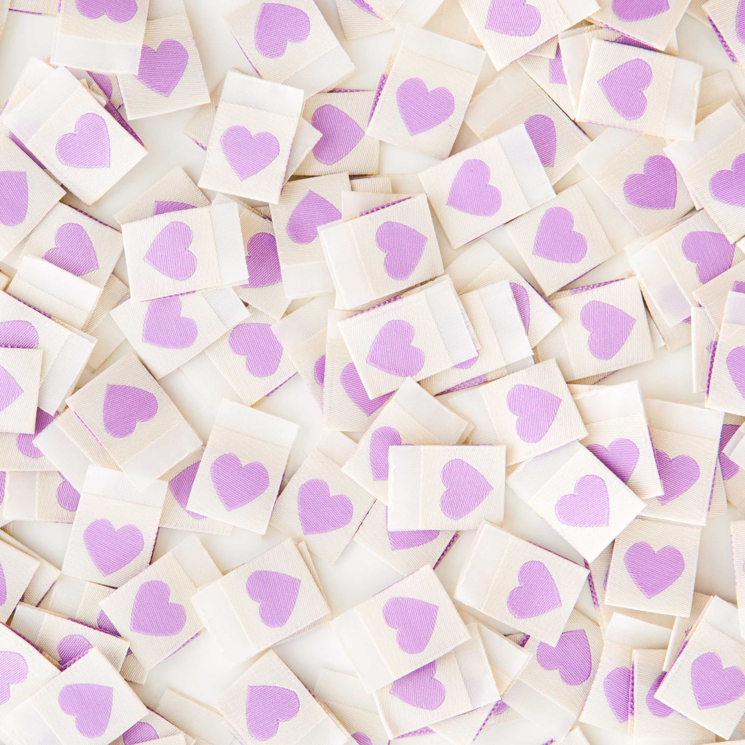 White sew in labels with purple hearts scattered in a heap