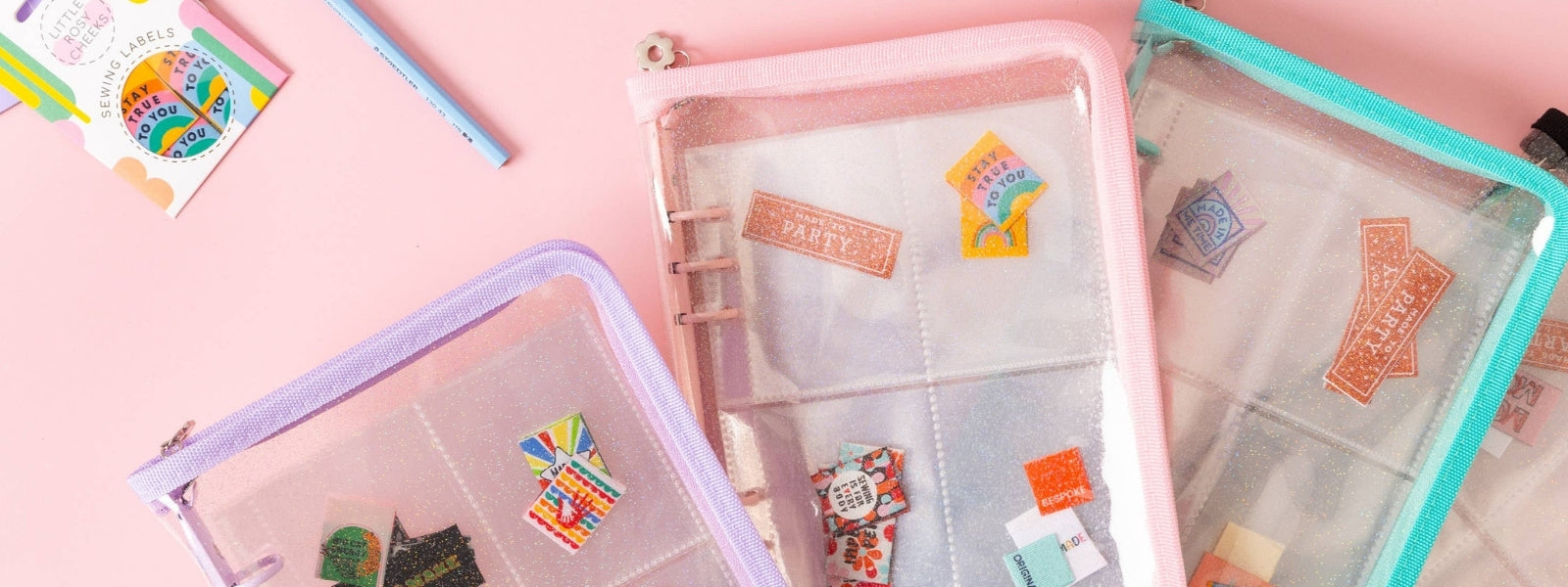 Transparent pouches with colorful labels on a pink background