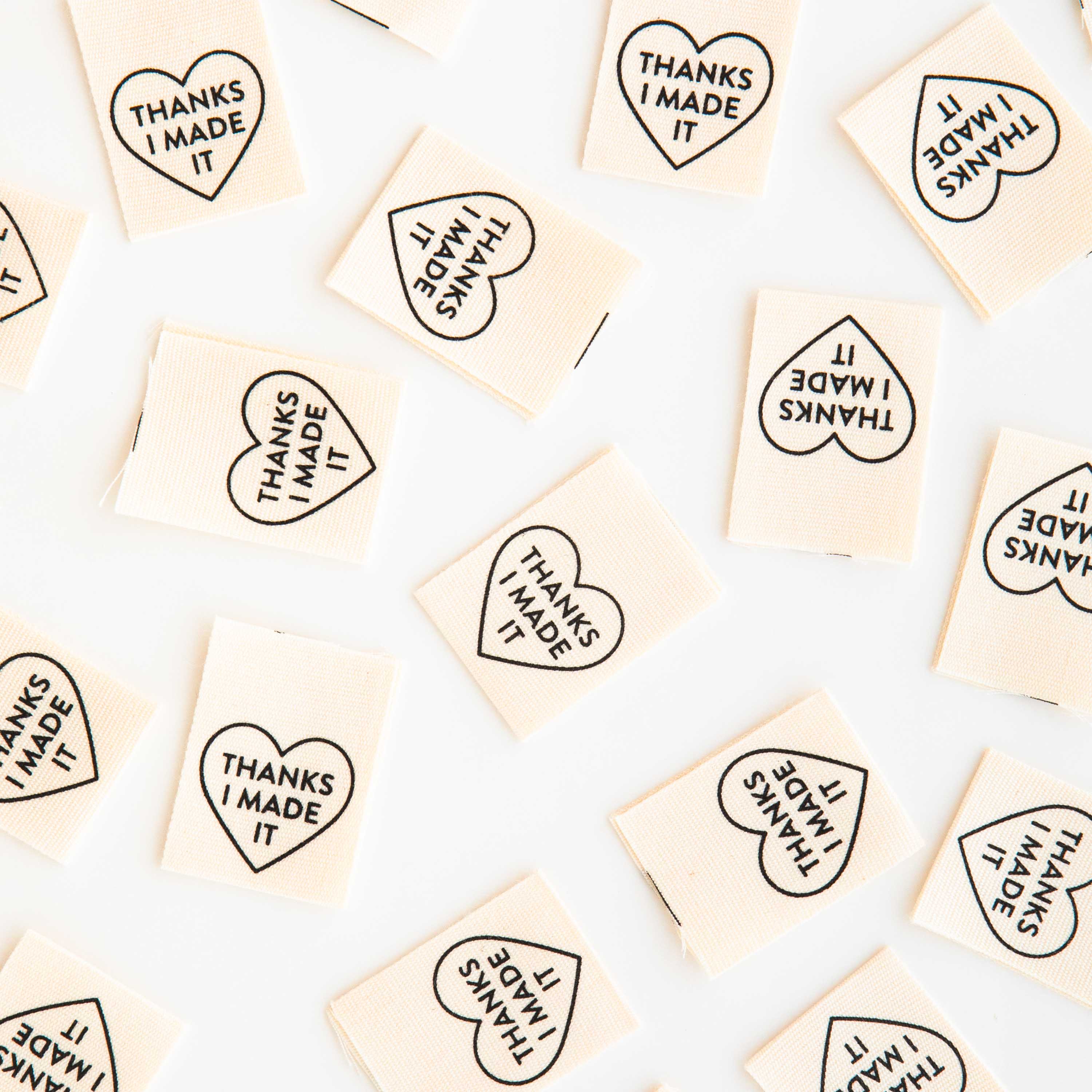Woven Labels scattered around the image, with the heart shaped design and text saying &