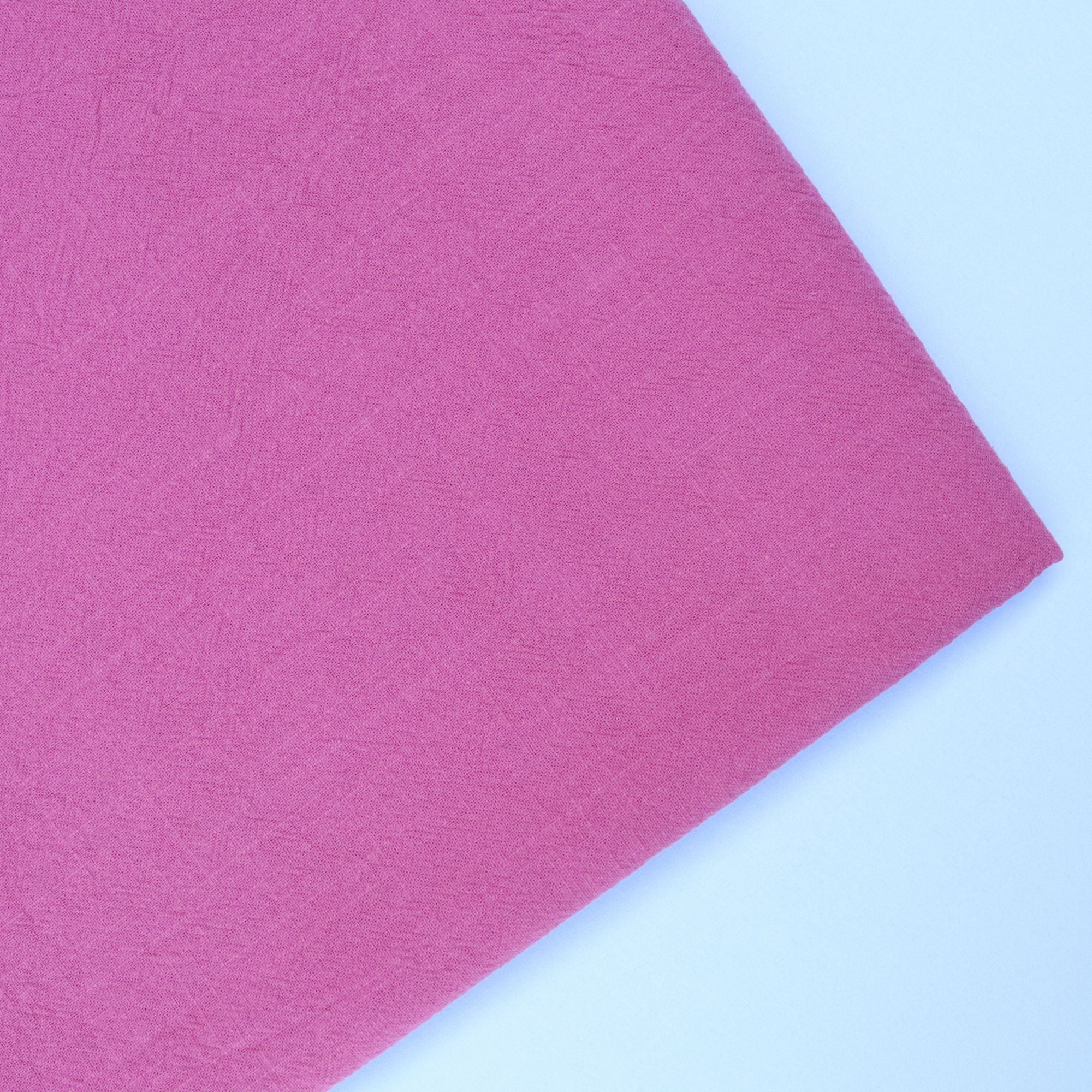 Rose coloured cotton fabric on a white background folded