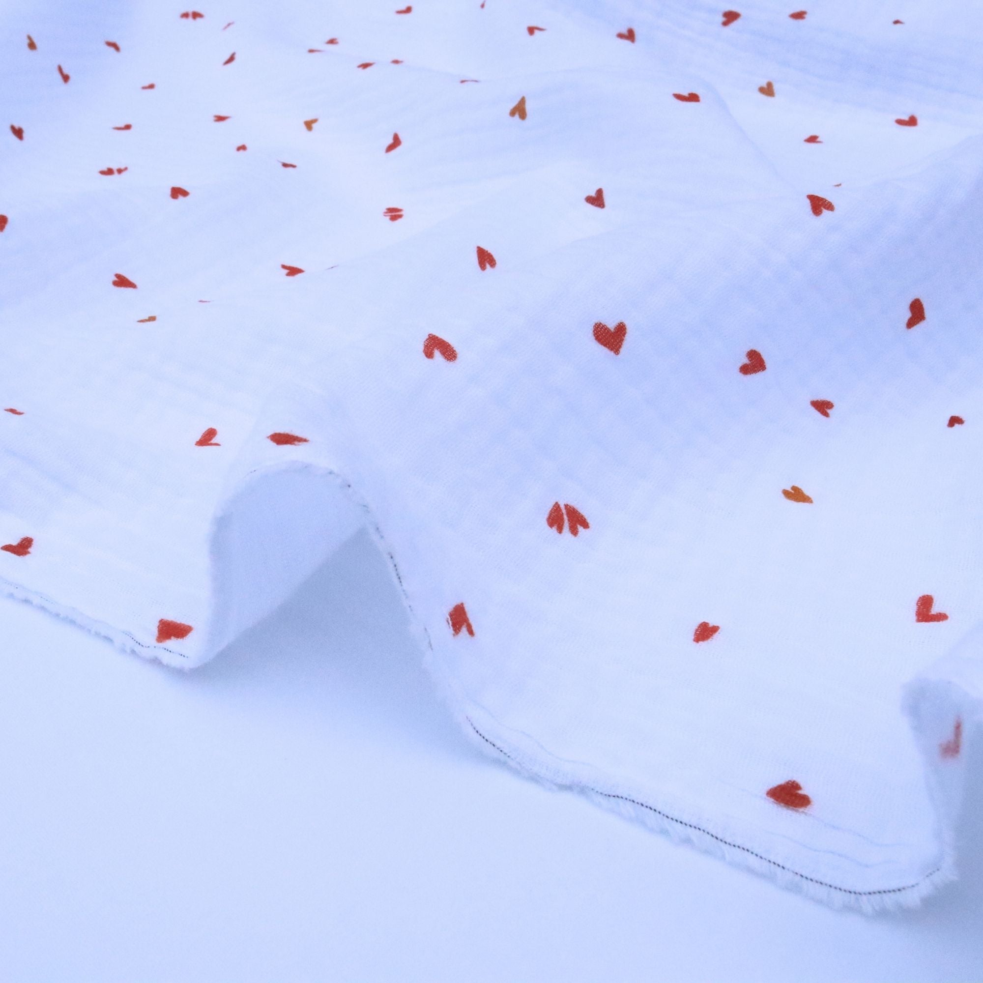 White fabric with red heart patterns on a light background