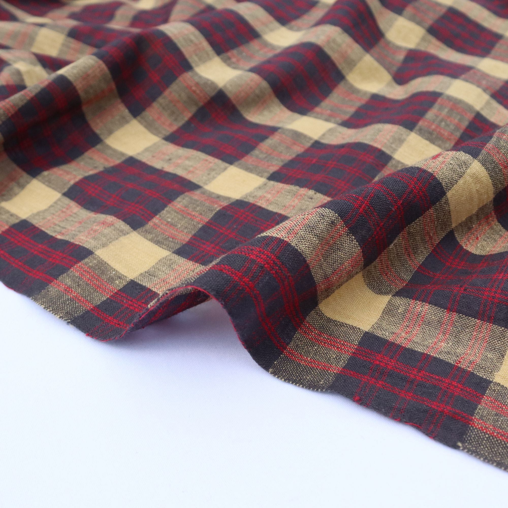 Plaid fabric with red, navy, and yellow colours on a white background