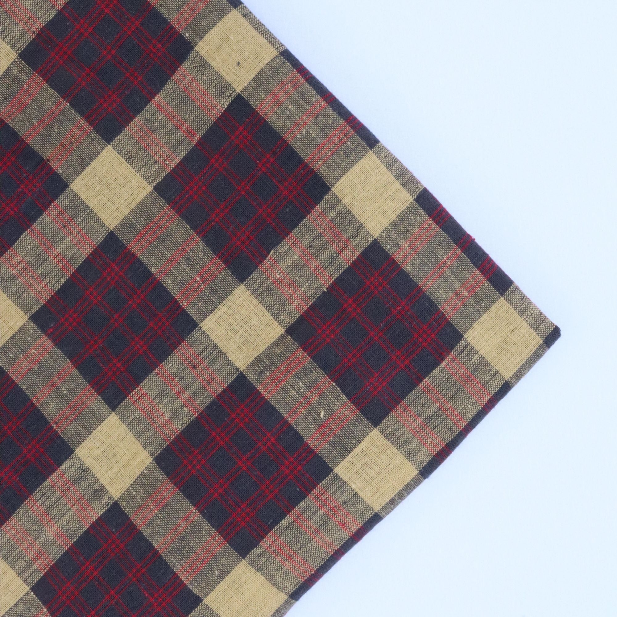 Plaid fabric with red, beige, and navy pattern on a light blue background