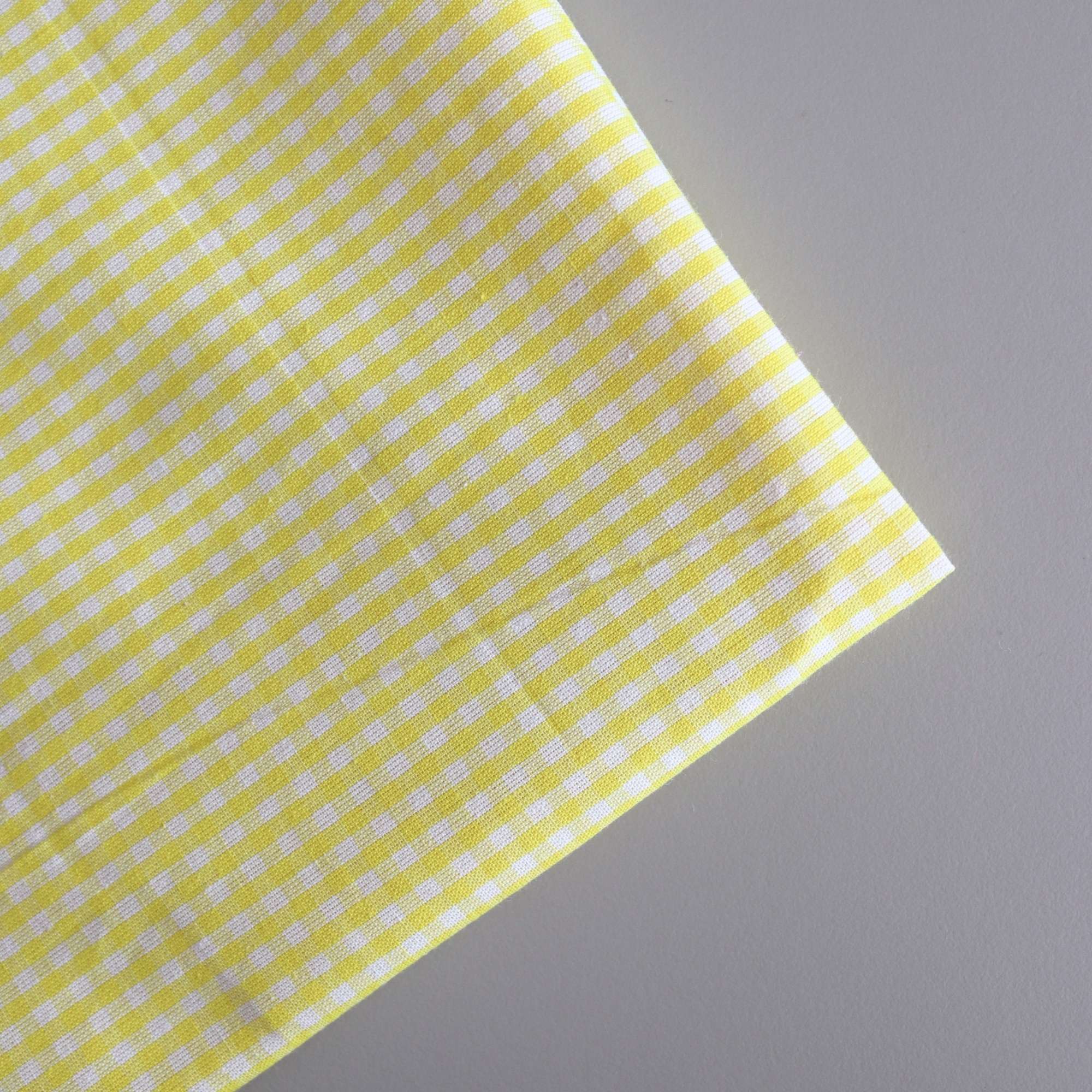 Close-up of yellow fabric with white stripes on a gray background