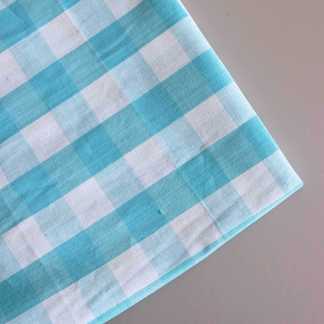 Aqua Blue Gingham Check Fabric folded on the table