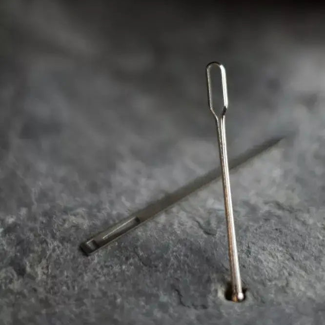 Two metal needles on a dark textured surface