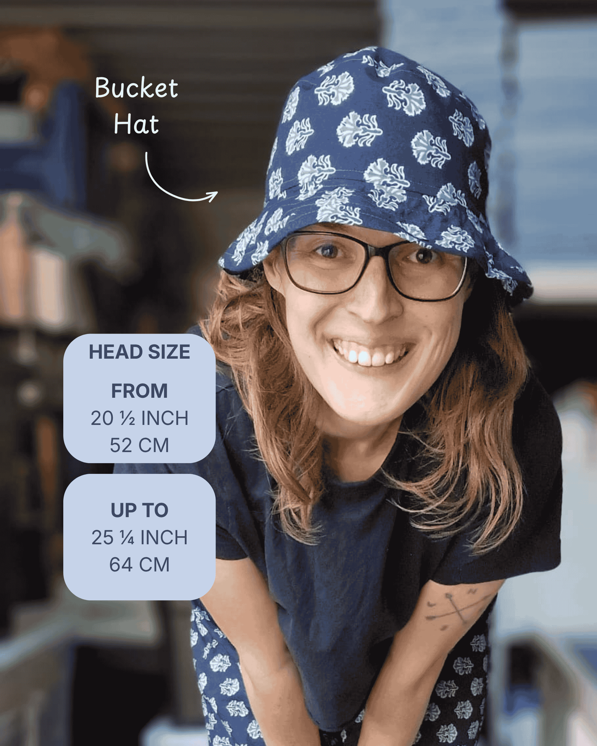 A woman wearing a navy blue bucket hat with a white floral pattern, shown in a lifestyle setting with text overlays detailing the head size range from 20 1/4 to 25 1/4 inches.