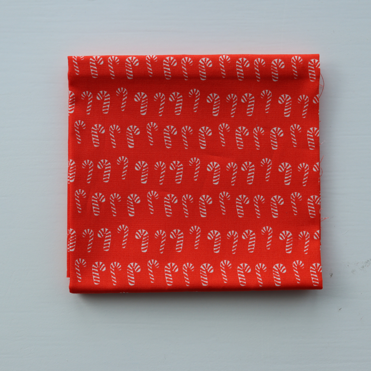Red fabric with white candy cane pattern on a light gray background