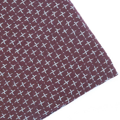 Close-up of fabric with white cross pattern on a brown background