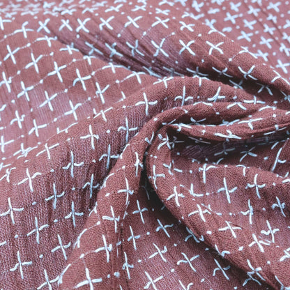 Close-up of a fabric with a pattern of white crosses on a maroon background