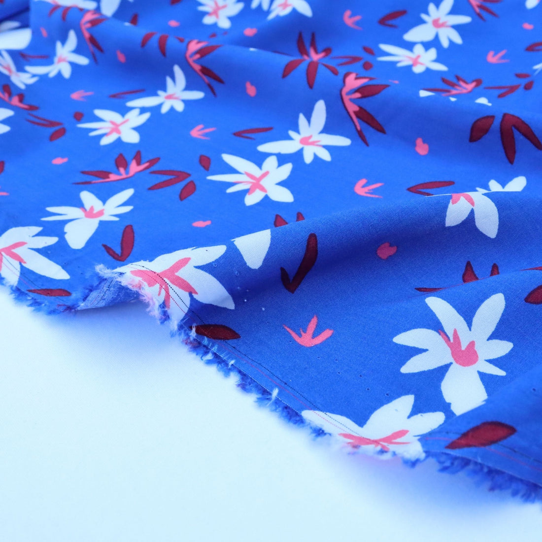 Floral fabric with white flowers and red leaves on a blue background