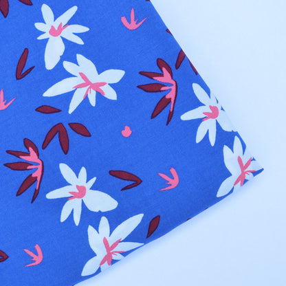 Floral patterned fabric with white, pink, and red flowers on a blue background