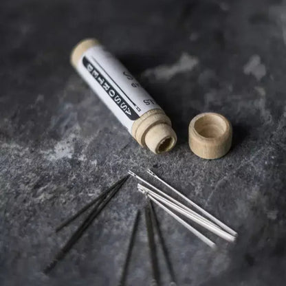 Wooden spool with sewing pins on a dark textured surface