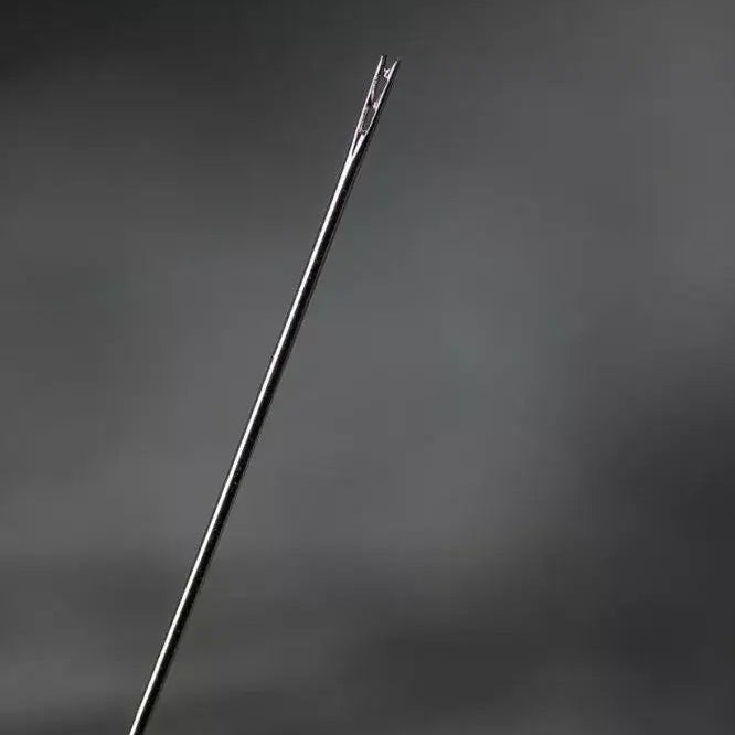 Close-up of a needle held by a hand against a dark background