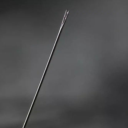 Close-up of a needle held by a hand against a dark background