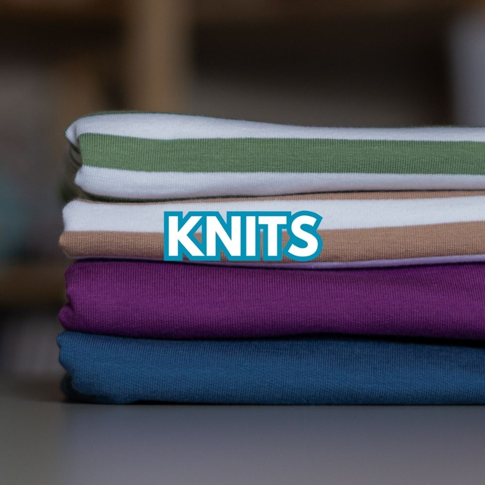 Stack of ribbed knit fabrics in green, beige, white, purple and blue – soft stretch fabrics for sewing at Sew Eco Fabrics