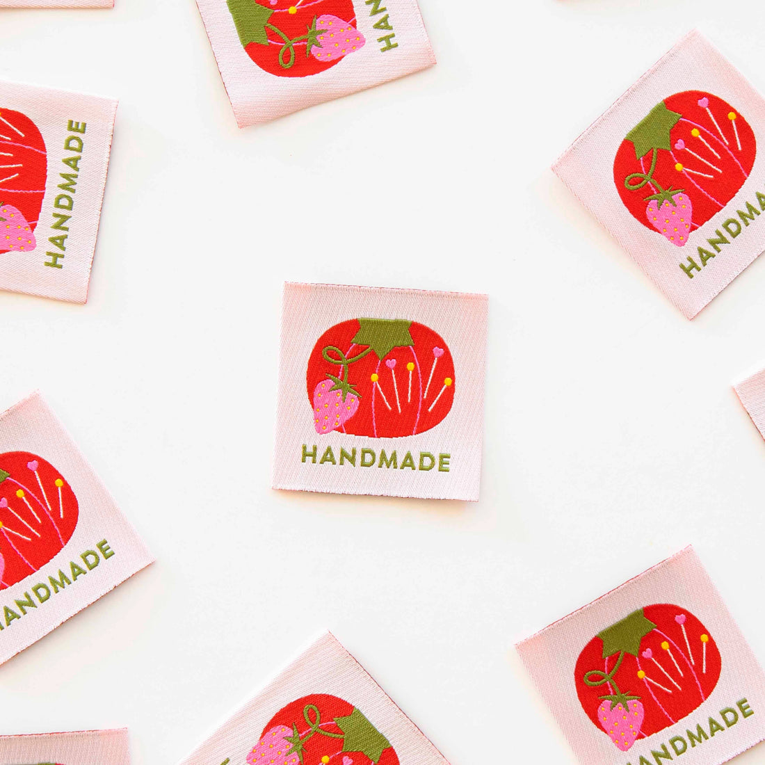 Sew in Labels with Tomato Pin Cushion Design, on a white background. Label in the centre with labels around the edges.