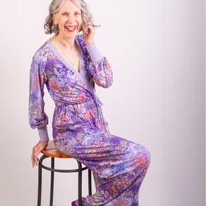 woman wearing purple jumpsuit, perched on a stall
