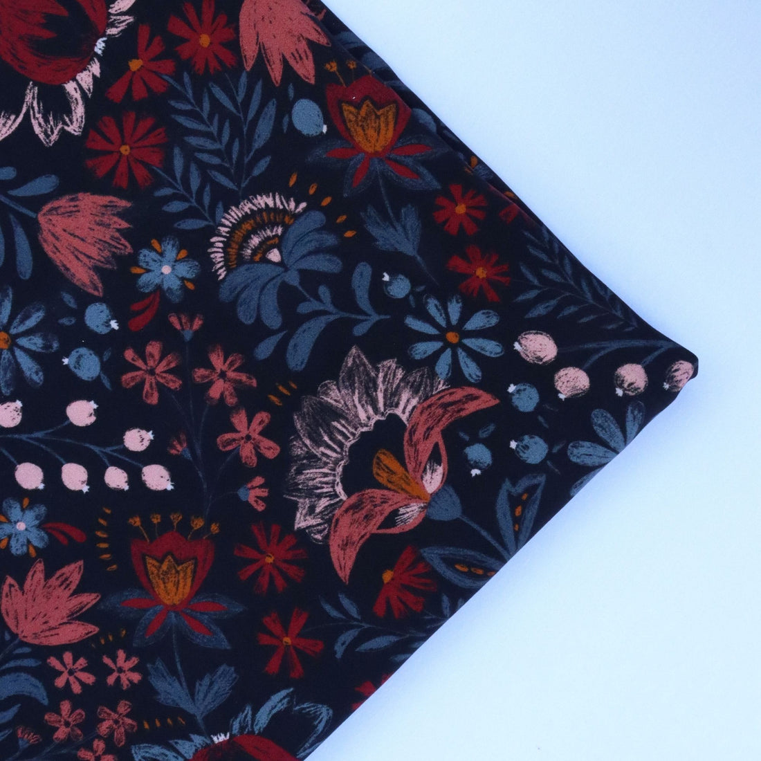 Floral fabric with red, pink, and blue flowers on a dark background