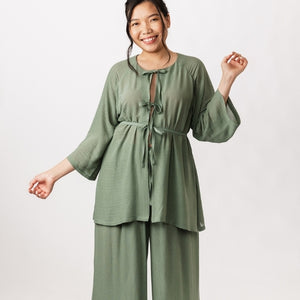 woman wearing a soft drapey dress tunic and trousers in green fabric, against a white background 