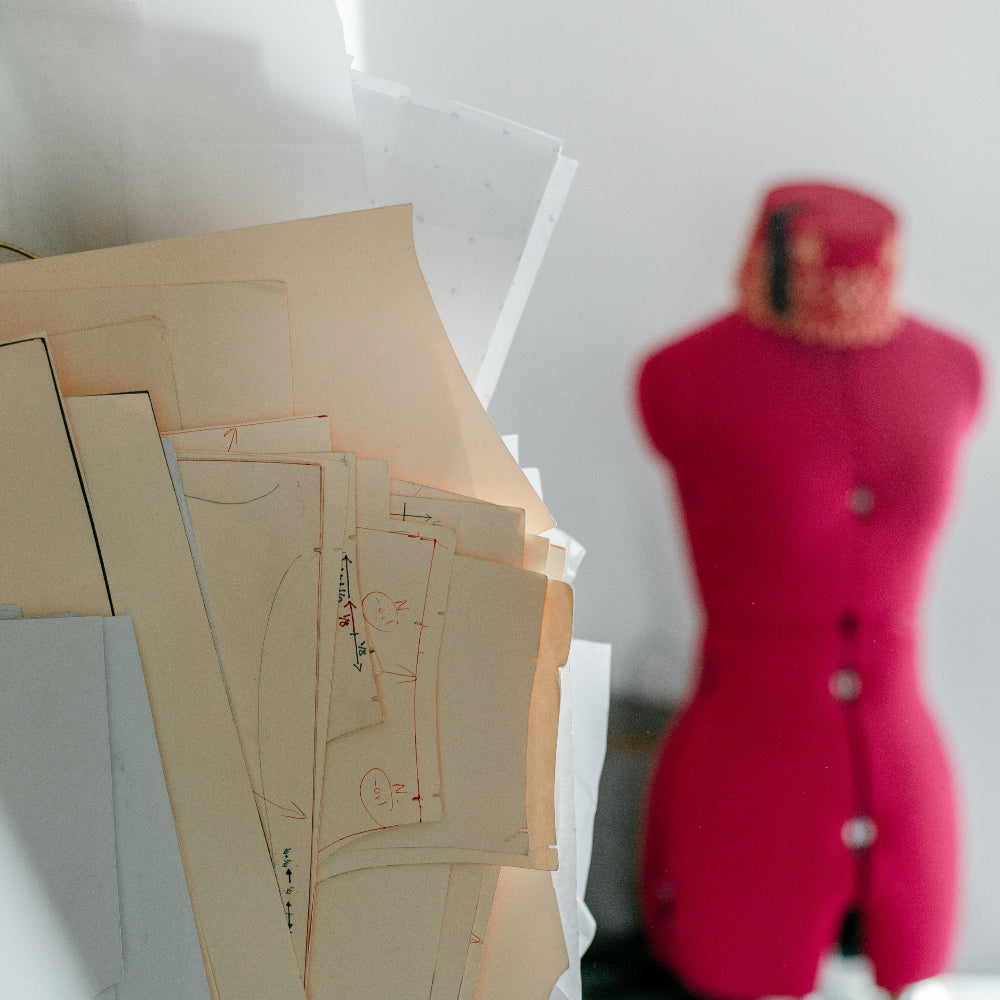 Pattern pieces on a table with a blurred mannequin in the background