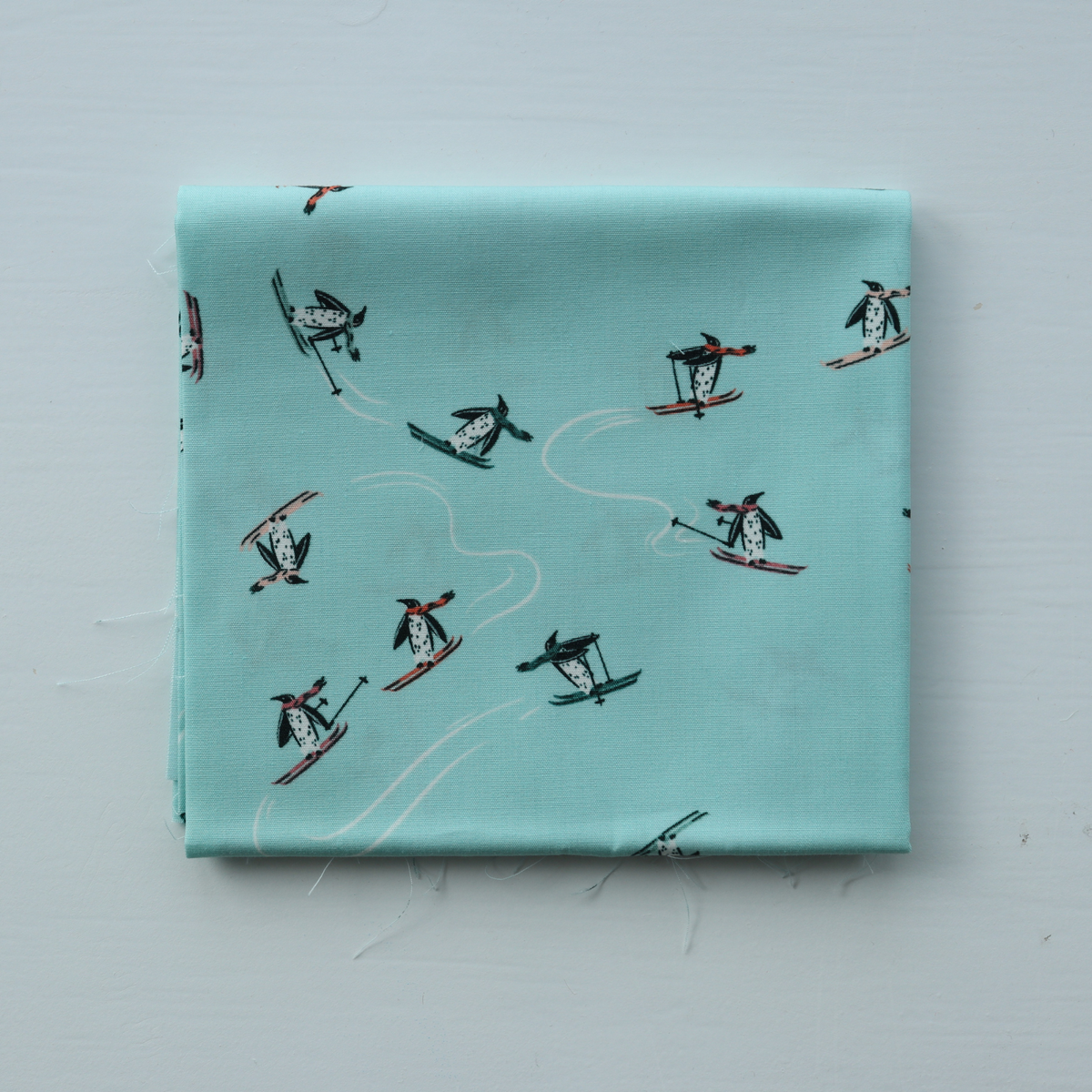 Folded fabric with penguin pattern on a light blue background