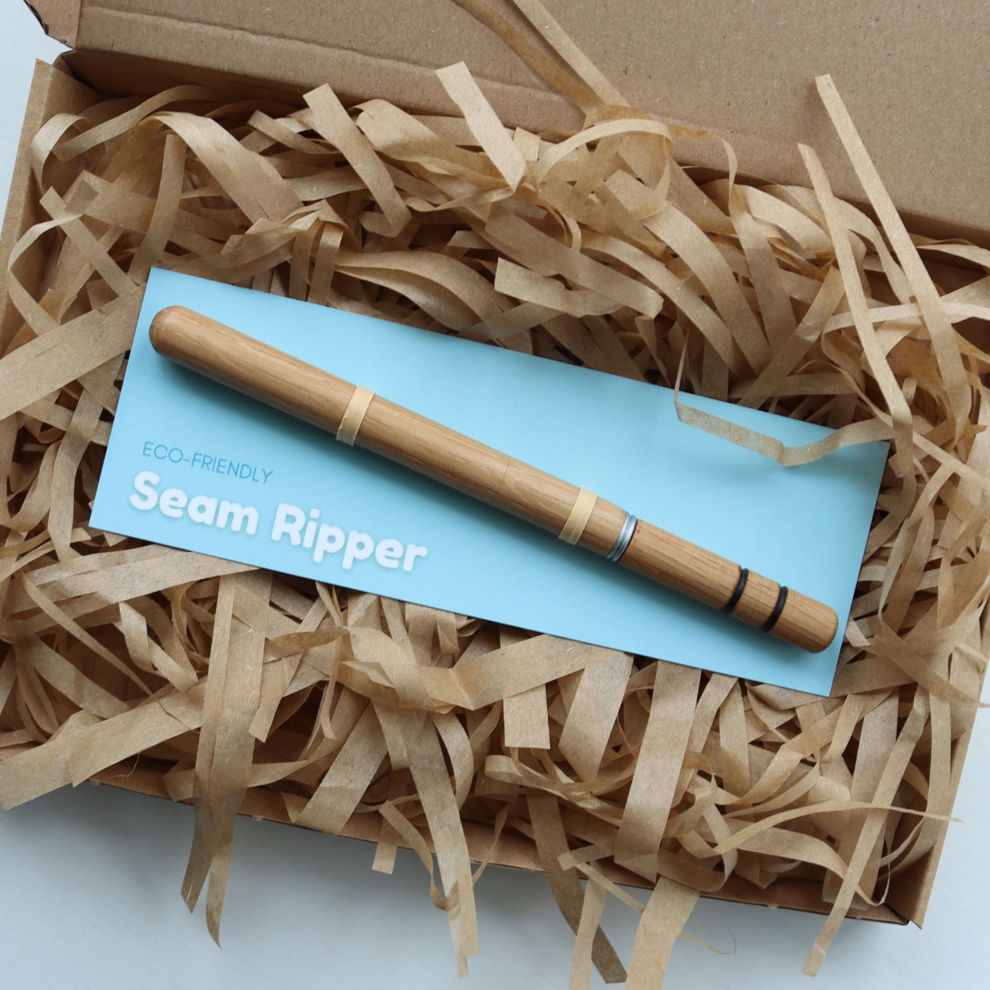 Wooden seam ripper on a blue card with &