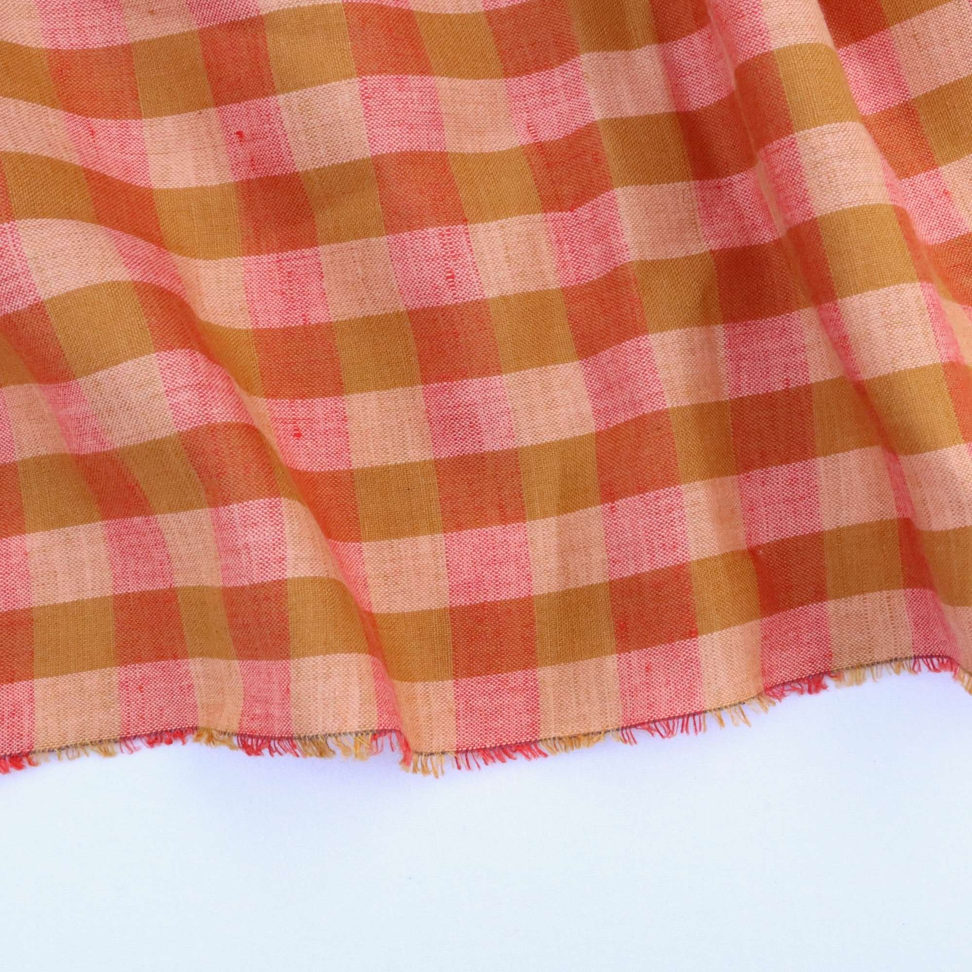 Close-up of a light and dark orange checkered gingham fabric on a white background