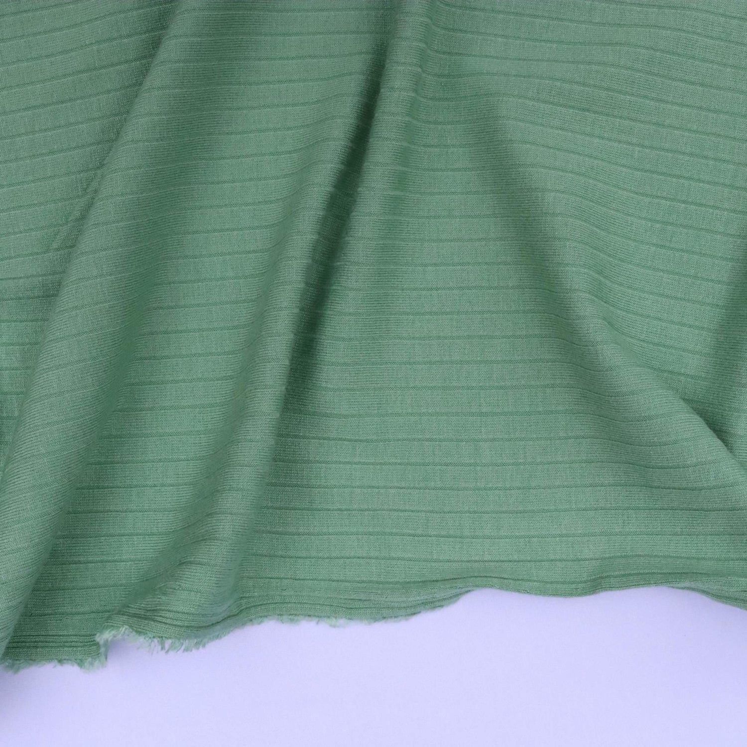 Green fabric with a ribbed texture on a white background