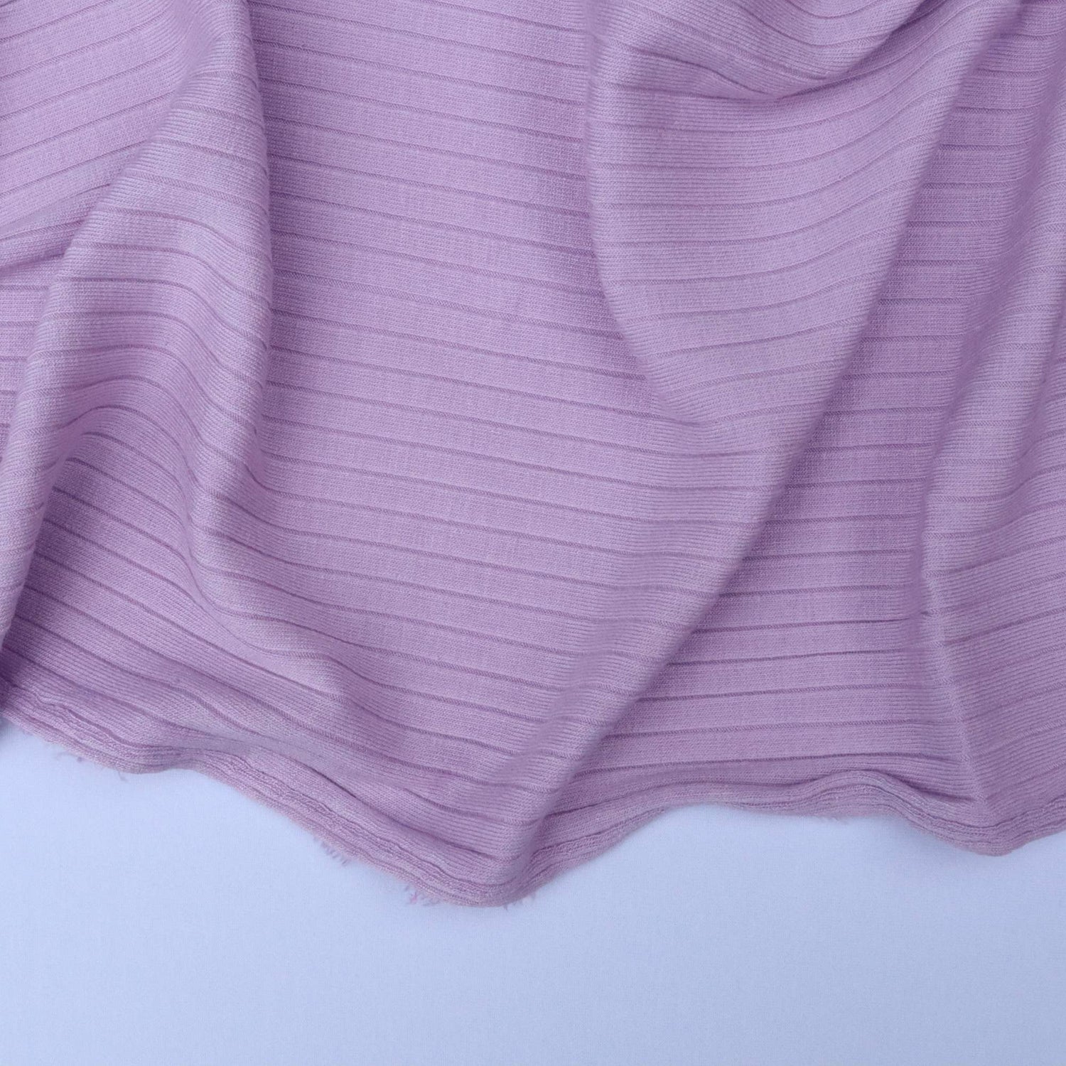 Close-up of purple ribbed fabric on a light gray background