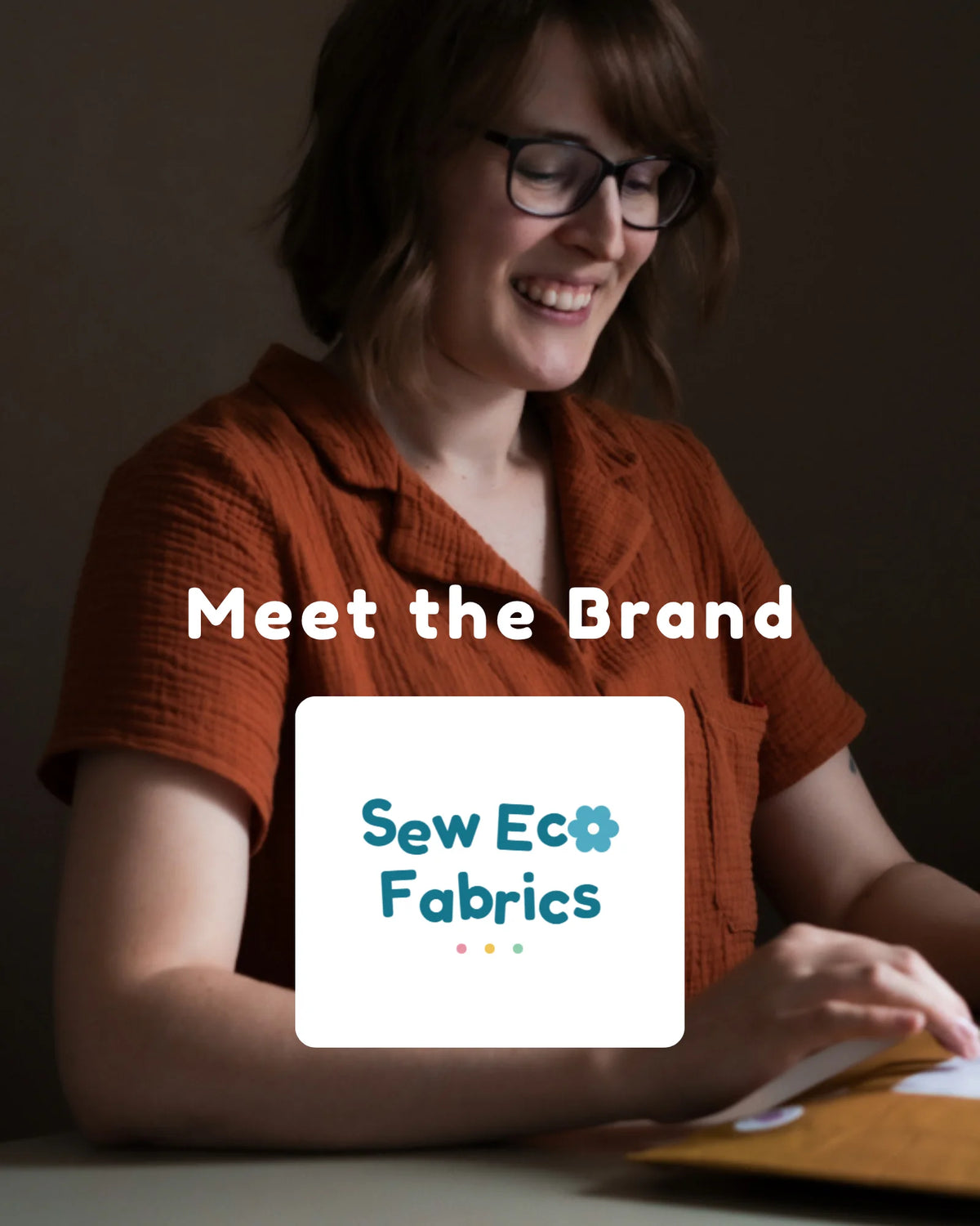 A smiling woman with glasses and short brown hair wears an rust-orange short-sleeve shirt while sitting at a desk. White text reads 'Meet the Brand' over a white square logo that says 'Sew Eco Fabrics' with a small blue flower icon.