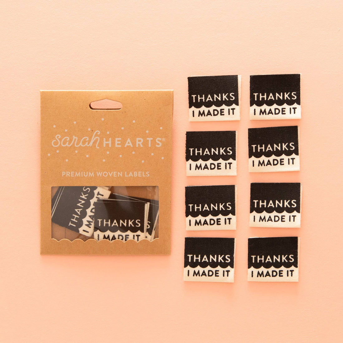 Sewing Labels laid out alongside its Sarah Hearts Packaging. The design is a mix of black and white, separated by a squiggle. The top s black and says &quot;Thanks&quot; underneath the squiggle is the white side that finished the text saying &quot;I Made it&quot; 