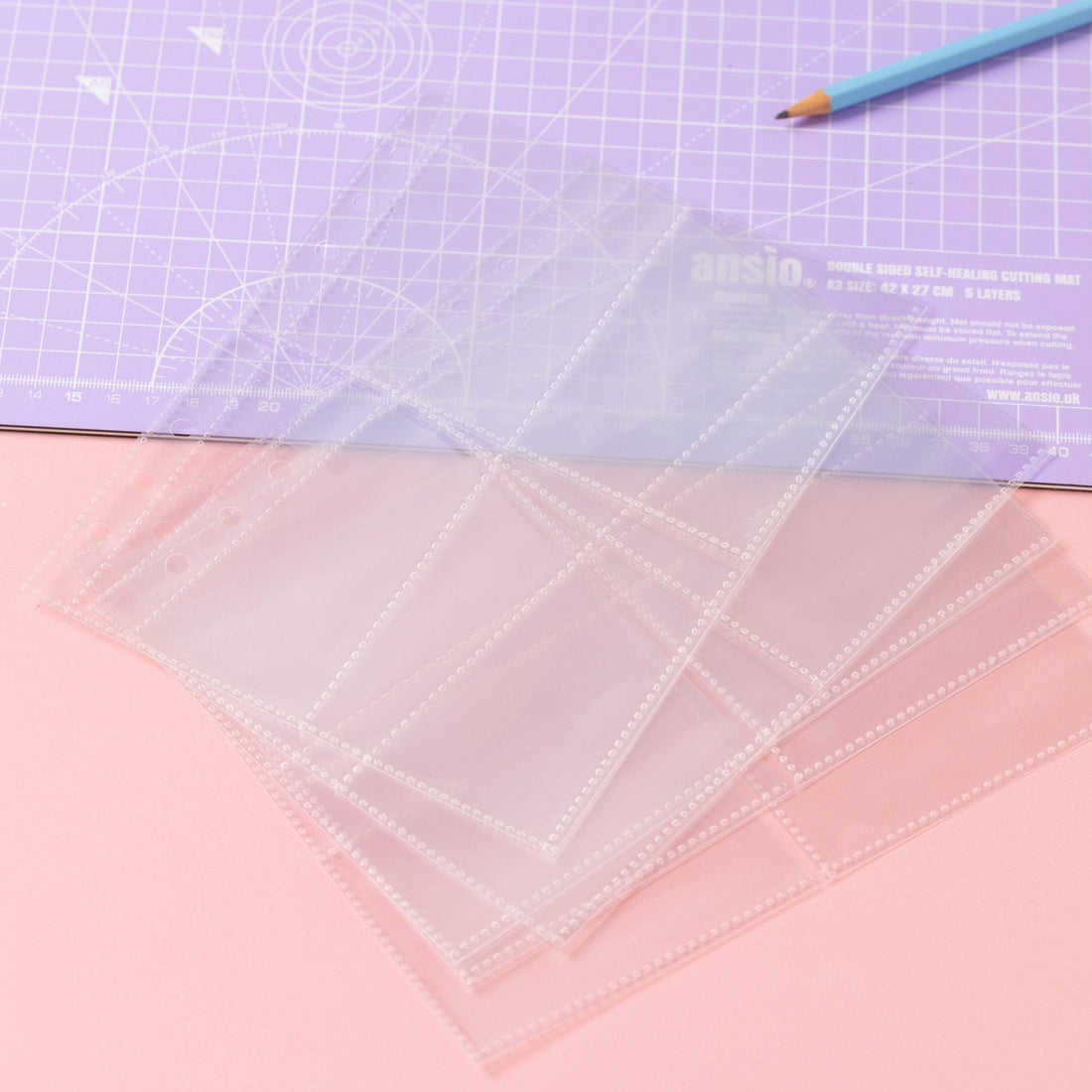 Clear plastic sheets for the sewing label stash folder laid  out on the sewing table.