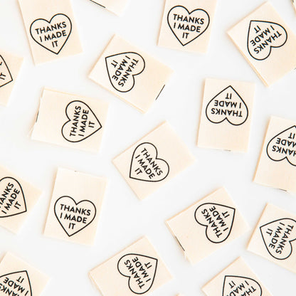 Woven Labels scattered around the image, with the heart shaped design and text saying &