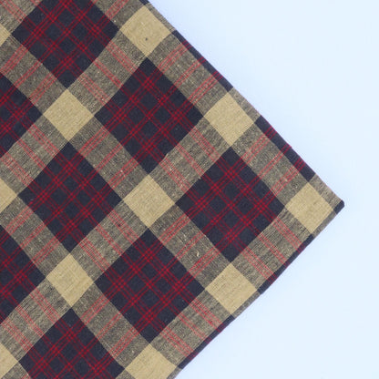 Plaid fabric with red, beige, and navy pattern on a light blue background
