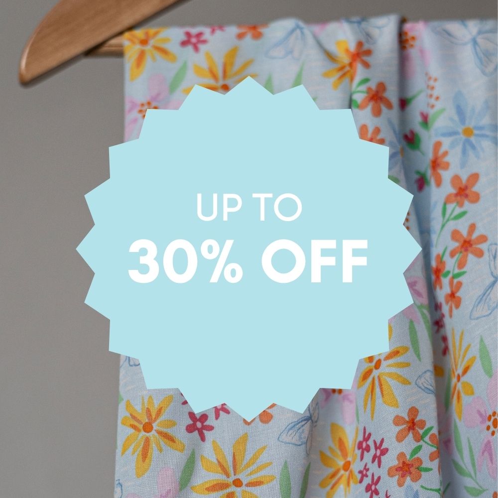 Floral fabric draped on a hanger with a blue starburst overlay reading “Up to 30% Off” — promoting a clearance sale on sewing fabrics